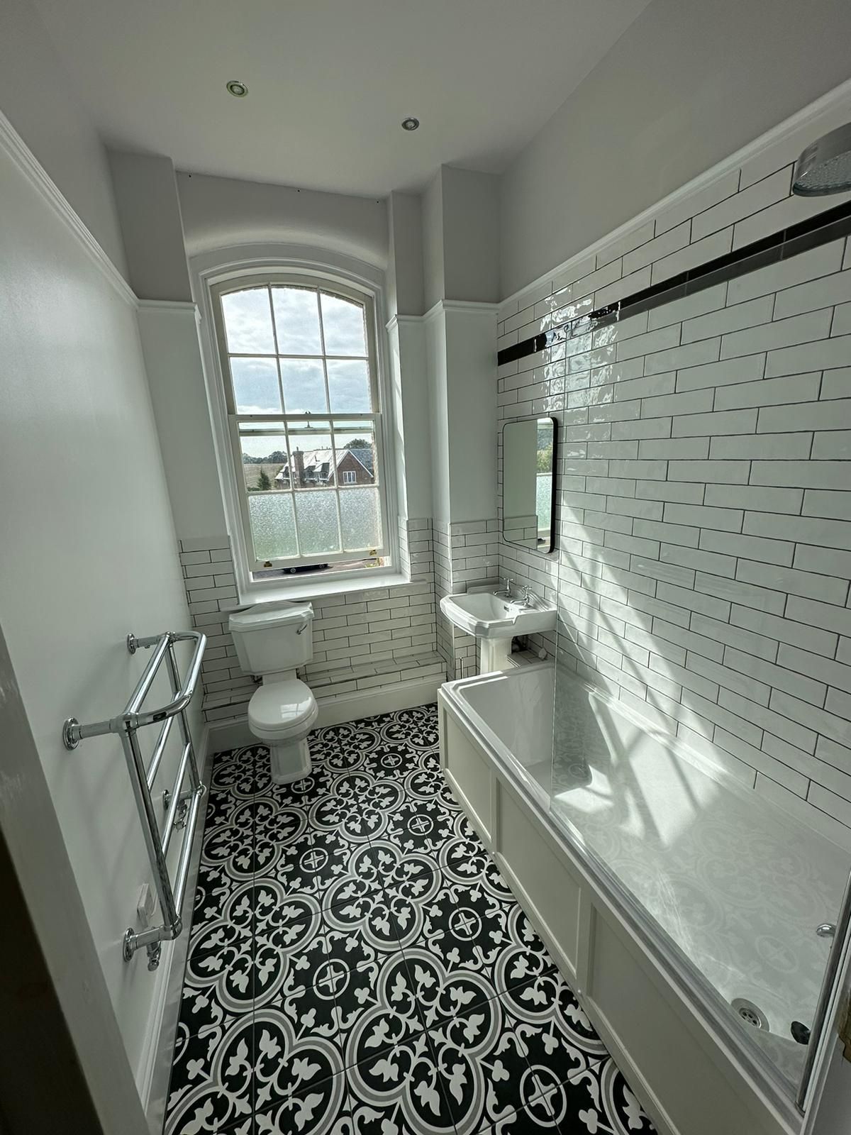 a bathroom with a bathtub , toilet , sink and window .
