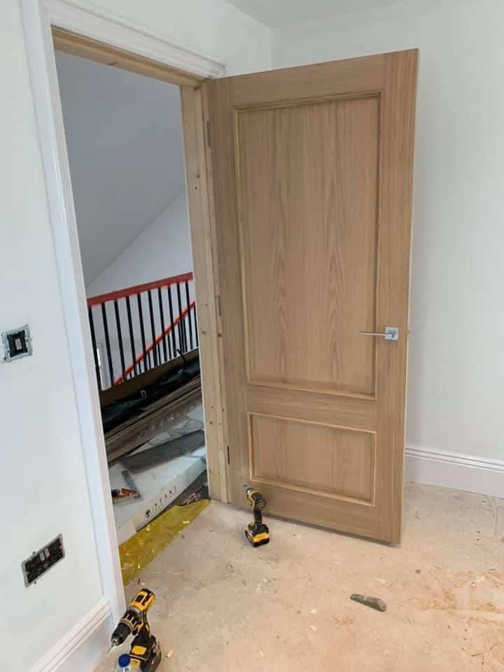 a wooden door is being installed in a room next to a staircase .