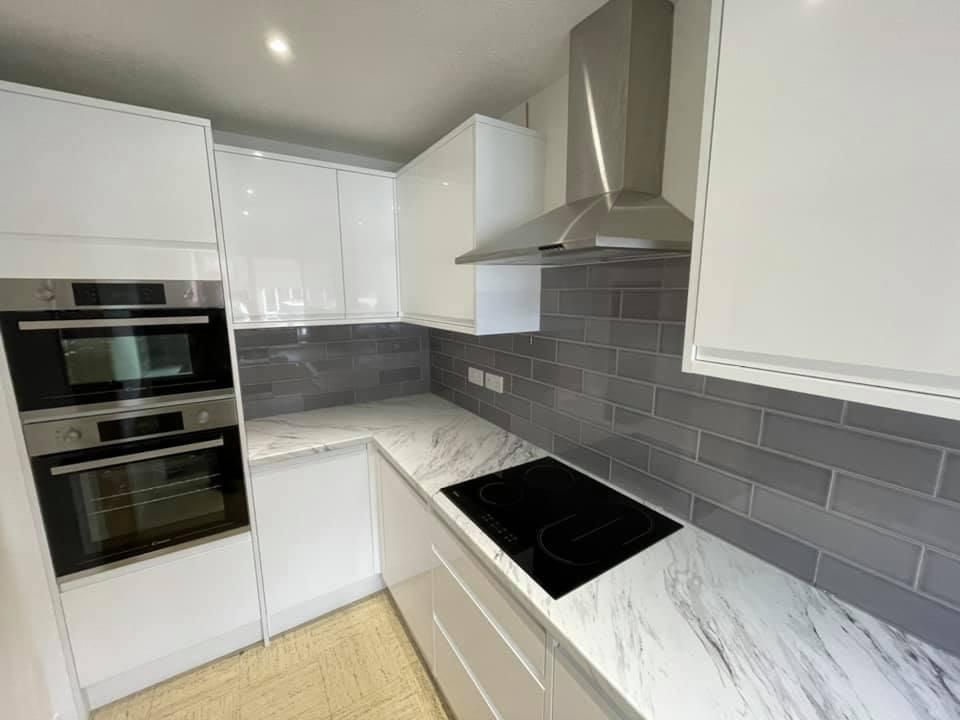 a kitchen with white cabinets , a stove top oven , and a hood .