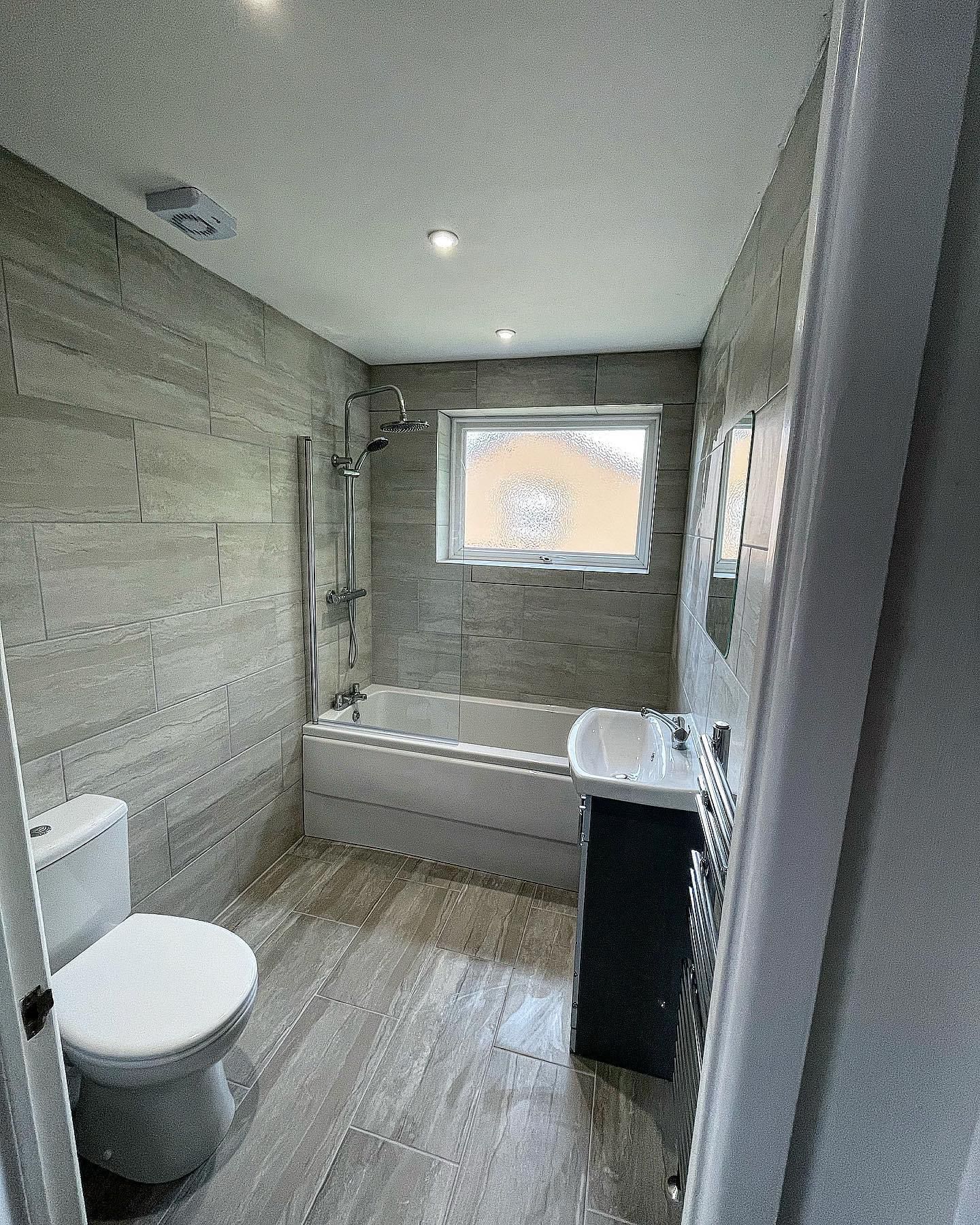 a bathroom with a toilet , sink , bathtub and window .