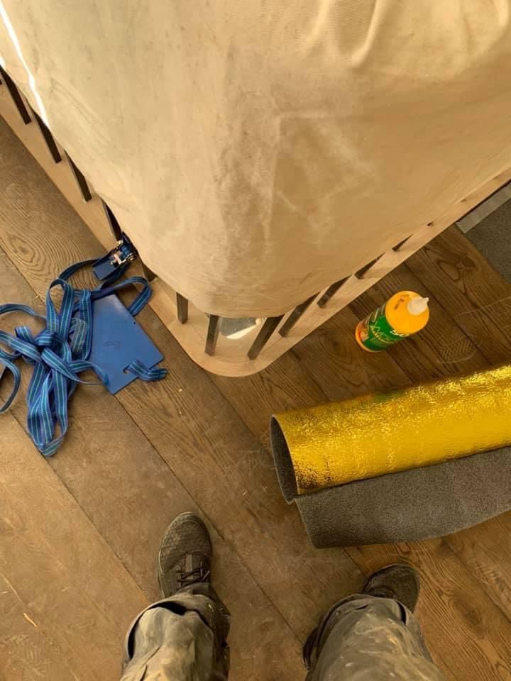 a person is standing on a wooden floor next to a bed .