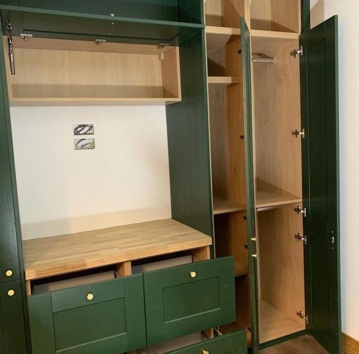a closet with green doors and drawers and a wooden shelf