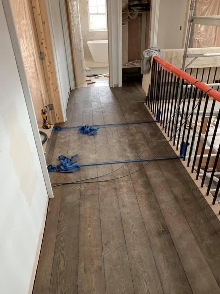 a hallway with wooden floors and stairs in a house under construction .