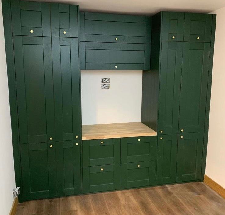 a room with green cabinets and a wooden floor .