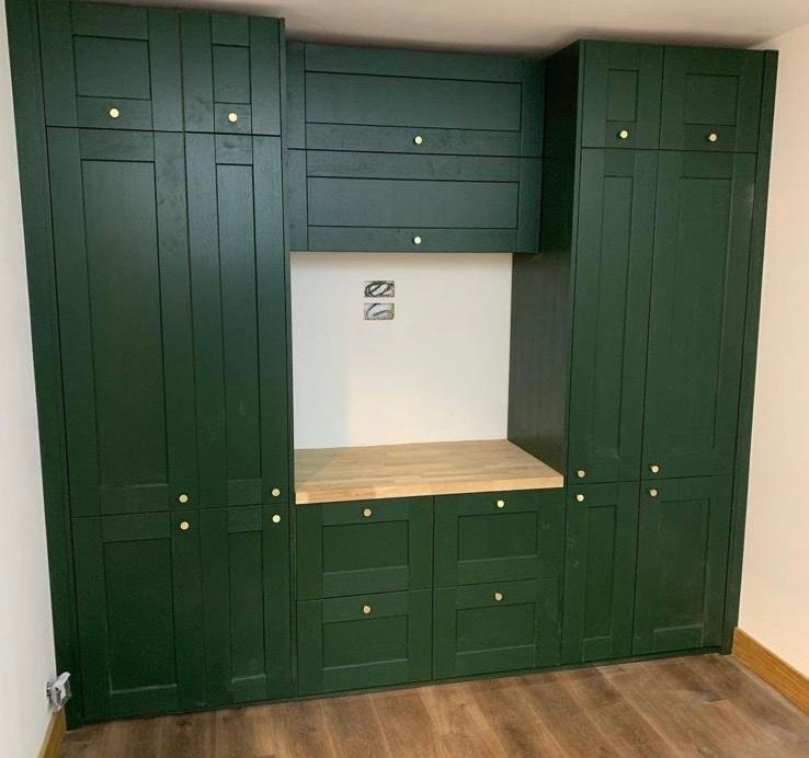 a room with green cabinets and a wooden counter top .