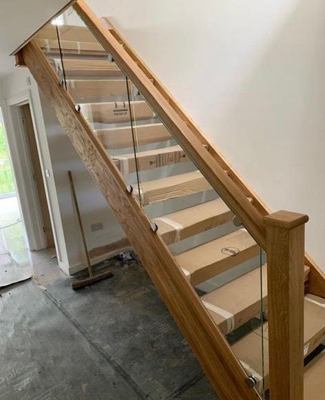 a wooden staircase with a glass railing is being built in a house .