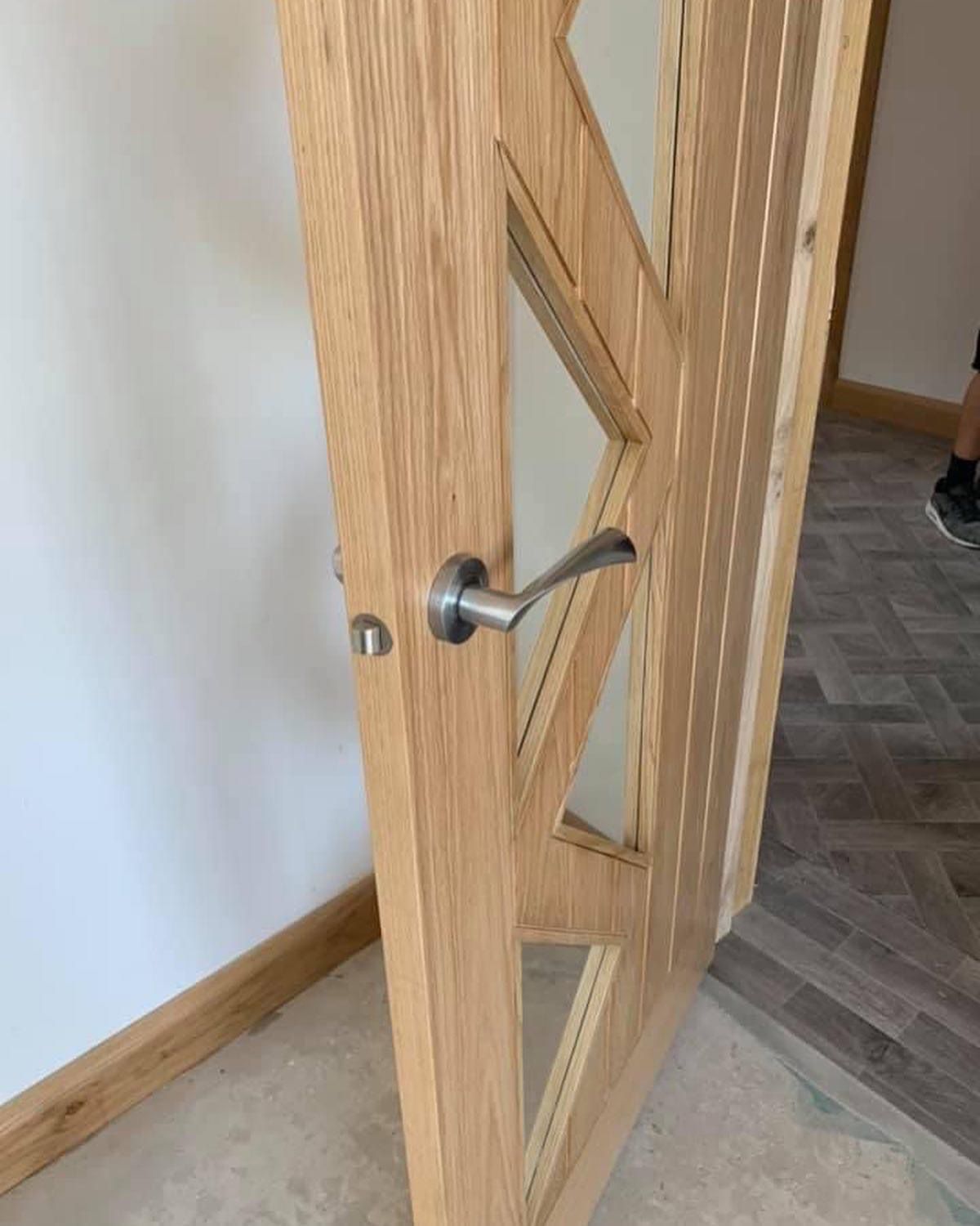 a wooden door with a stainless steel handle is open in a room .