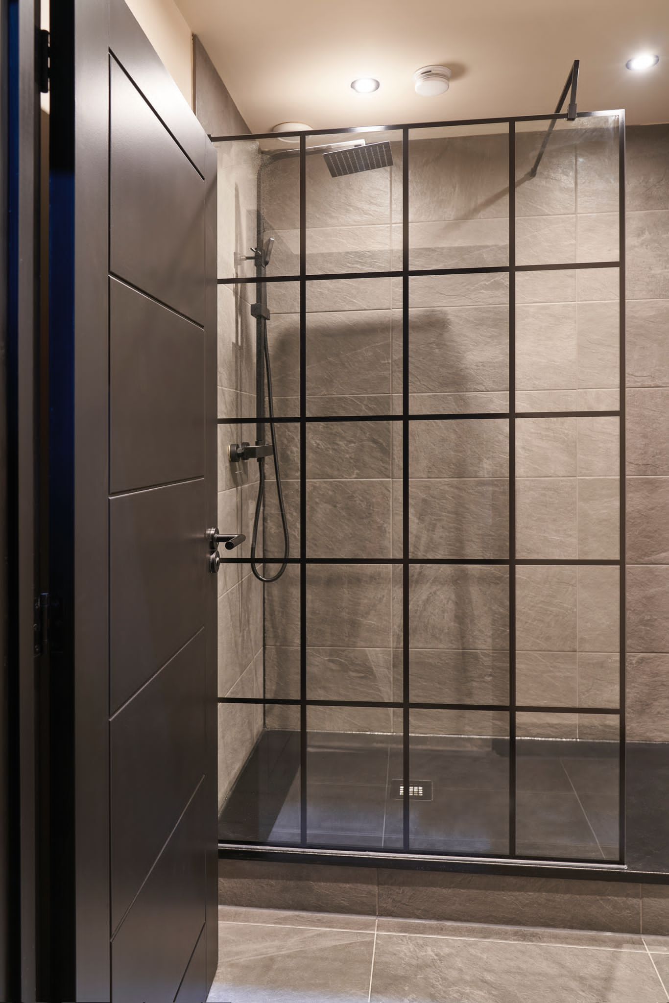 a bathroom with a walk in shower and a black door .