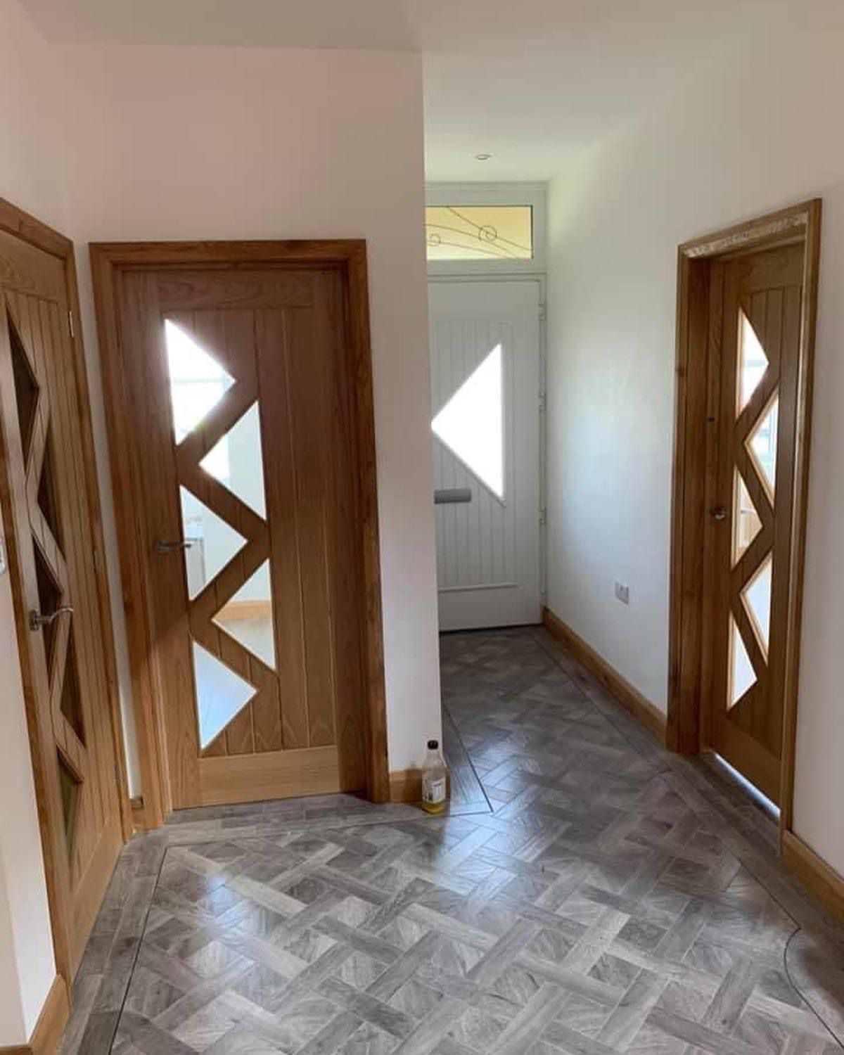 a hallway with wooden doors and a herringbone floor .