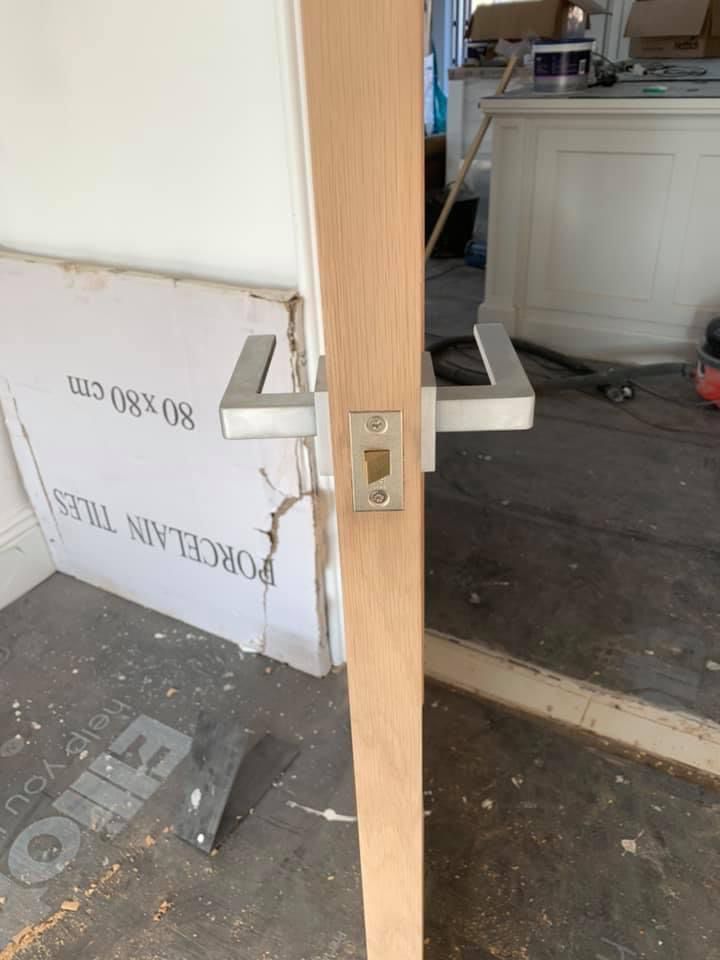 a wooden door with a metal handle is being built in a room .