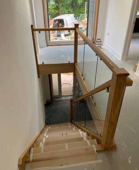 a wooden staircase with a glass railing and a window .