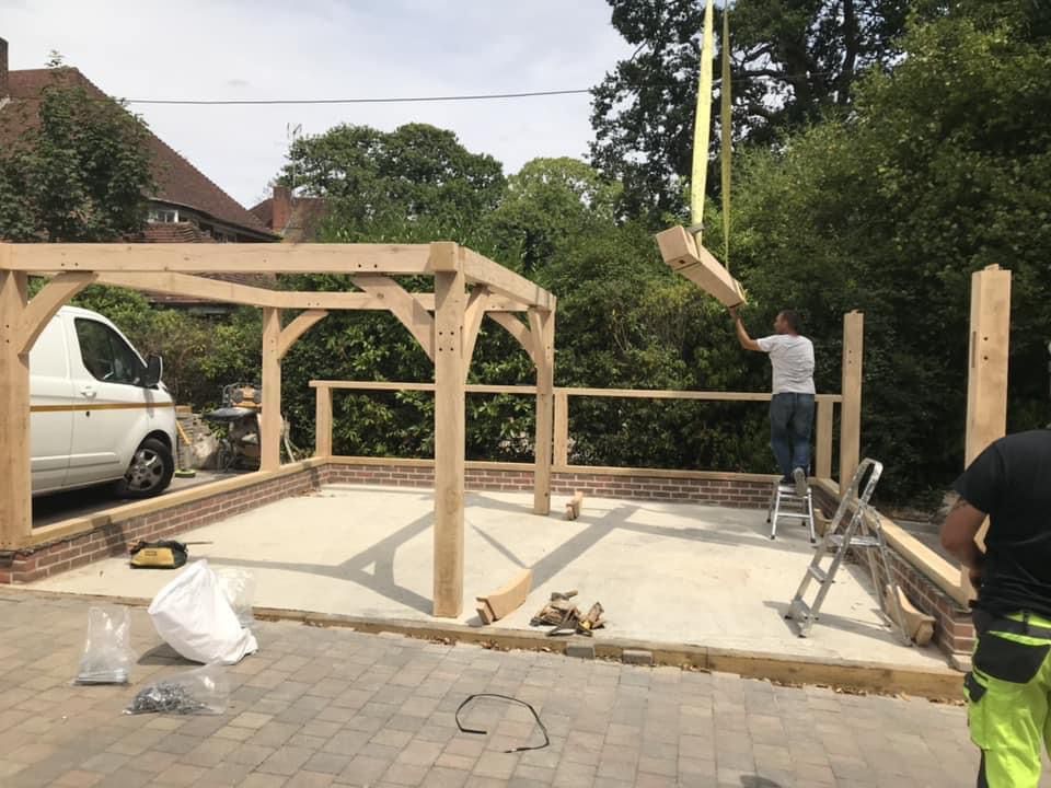 a man is standing on a ladder in front of a wooden structure being built .