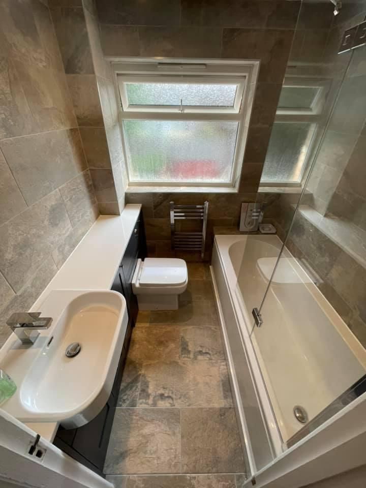 a bathroom with a sink , toilet , bathtub and window .