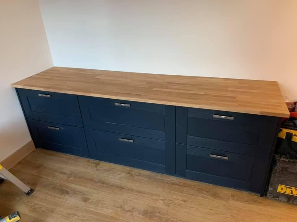 a long dresser with drawers and a wooden top in a room .