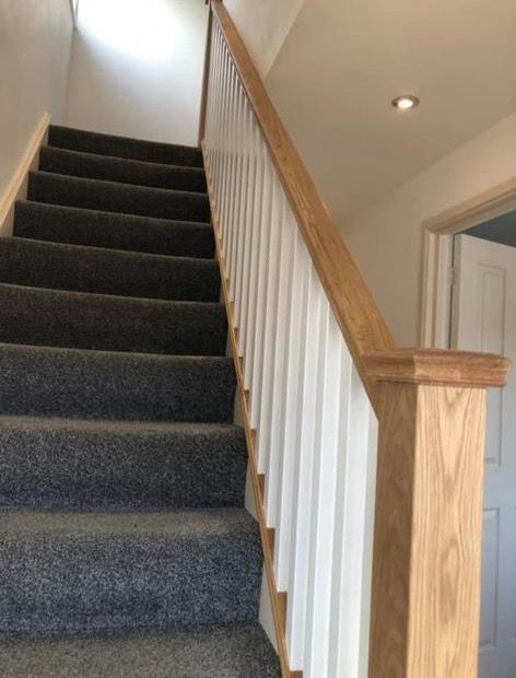 a set of stairs with carpeted steps and a wooden railing .