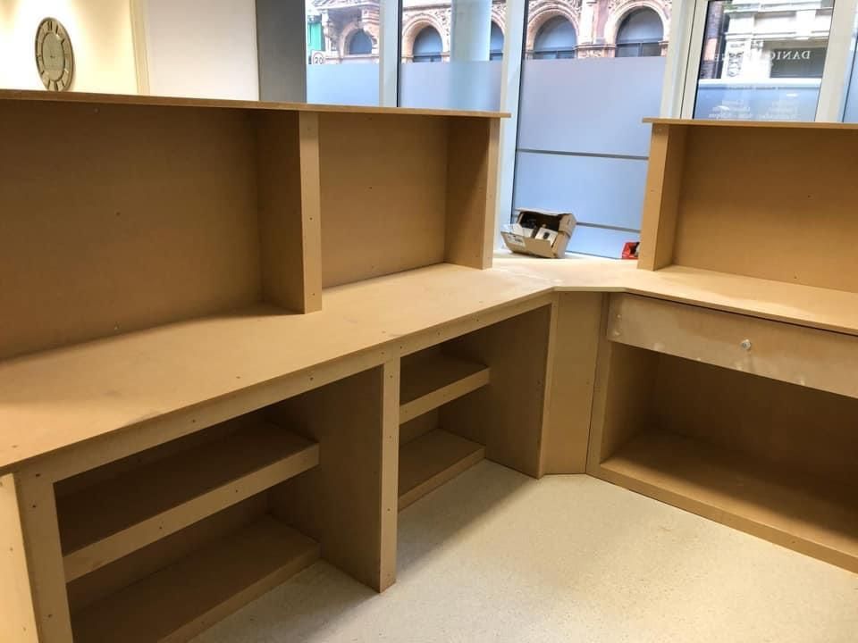 a wooden desk with shelves and drawers in a room with a window .