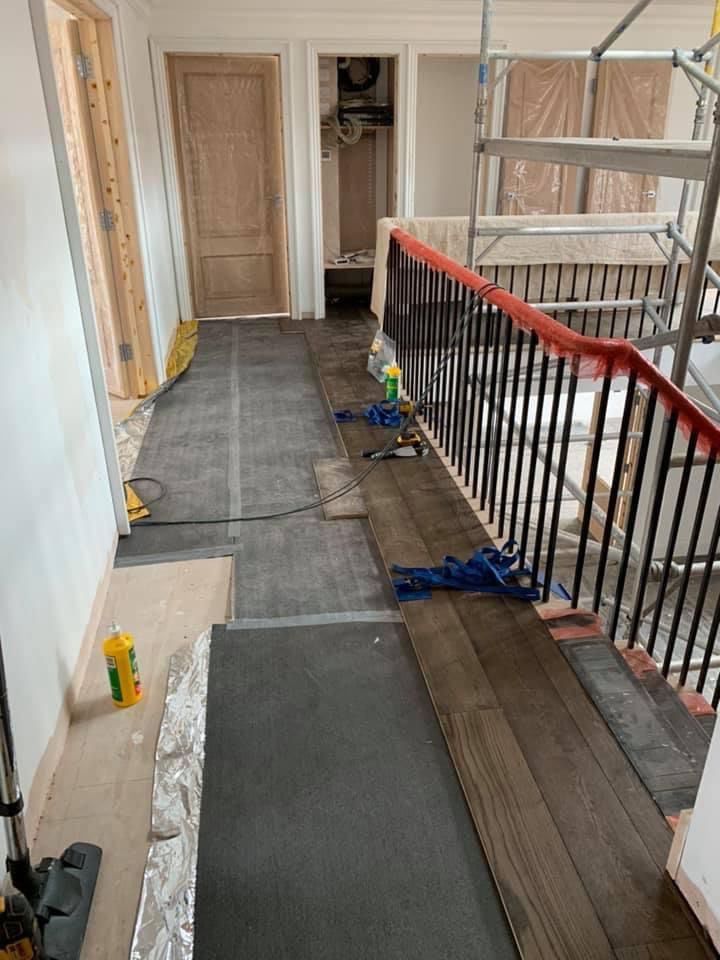 a hallway with a wooden floor and stairs under construction .