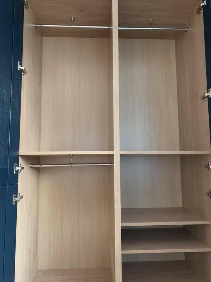 the inside of an empty wooden wardrobe with shelves and clothes racks .