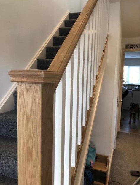 a staircase with a wooden railing and black carpet