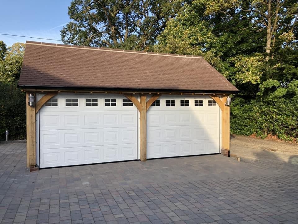 a garage with two white garage doors and a brown roof .