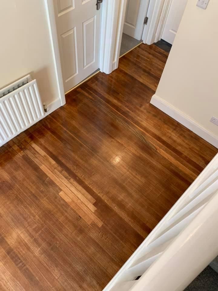 a wooden floor in a hallway next to a staircase .