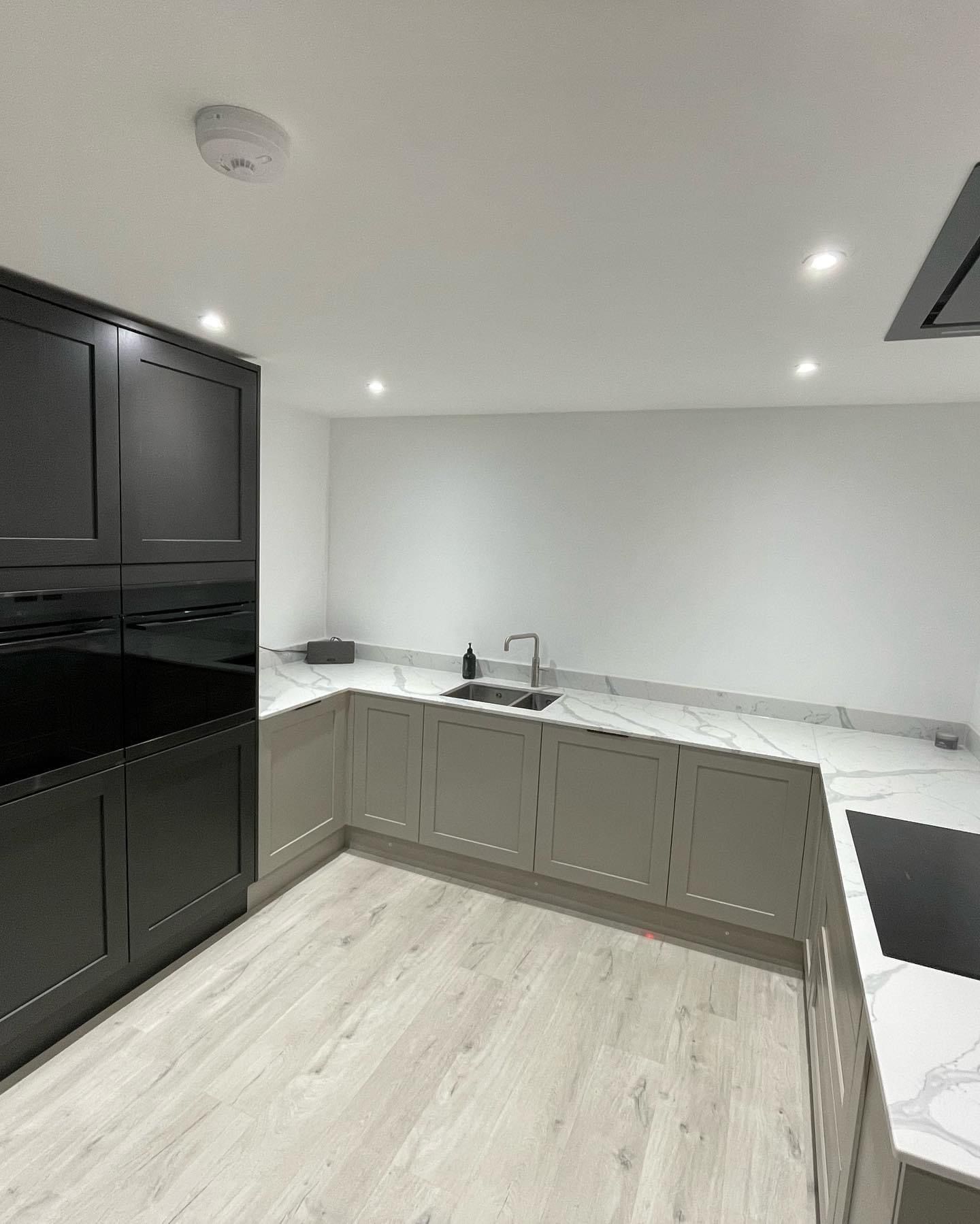 a kitchen with black cabinets , white counter tops , a sink , and a stove .