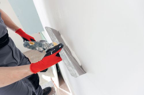 A person is plastering a wall with a spatula.