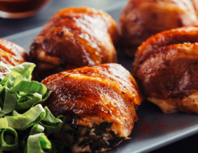 A plate of food with meat wrapped in bacon and green onions