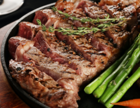 A steak with asparagus and carrots on a pan