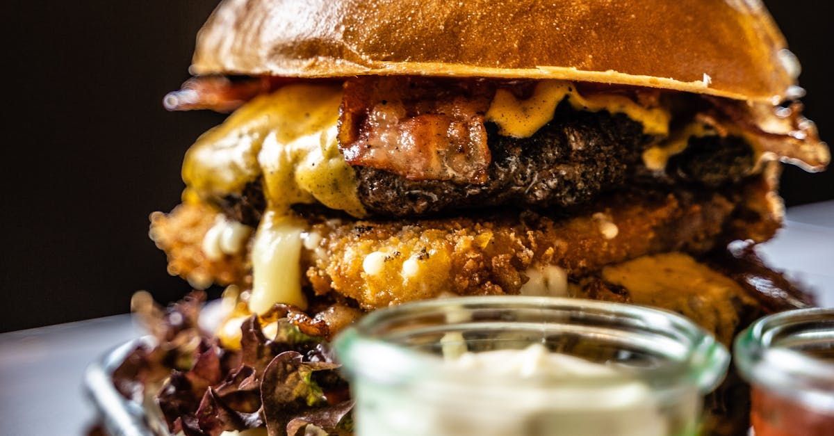 A close up of a hamburger on a plate with sauces.