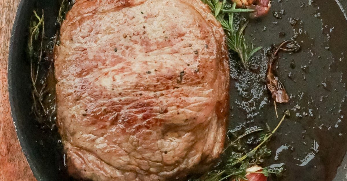 A large piece of meat is being cooked in a frying pan.