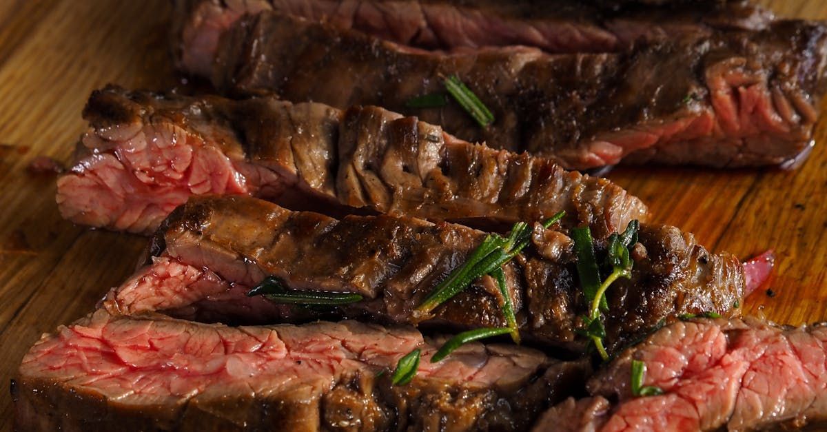 A close up of sliced steak on a wooden cutting board.