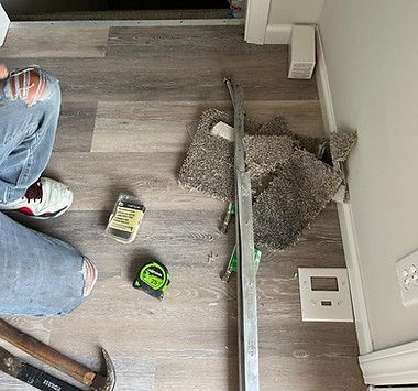 A person is sitting on the floor next to a hammer and tape measure