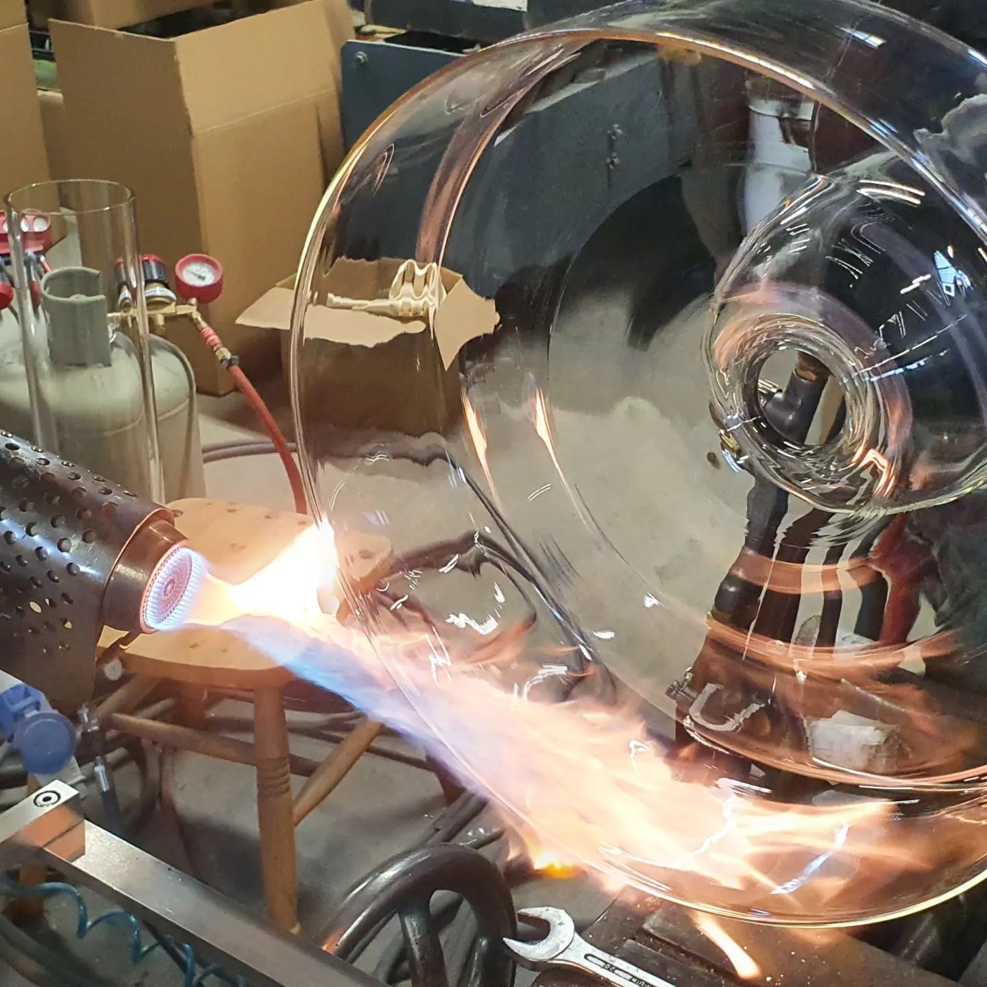 Un soffiatore di vetro usa una torcia per dare forma a una grande ciotola di vetro in un laboratorio.