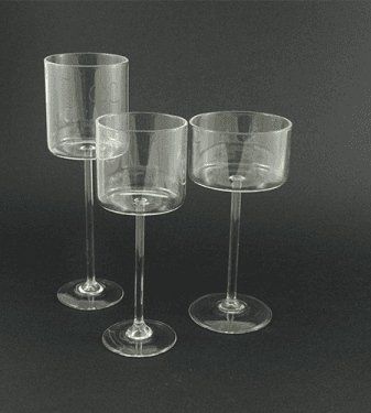 Tre fioriere con piedistallo in vetro trasparente su sfondo nero, di altezza variabile.