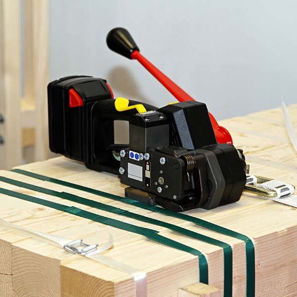 A strapping machine is sitting on top of a wooden box