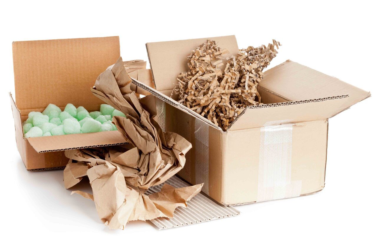 Two cardboard boxes filled with brown paper and green foam.