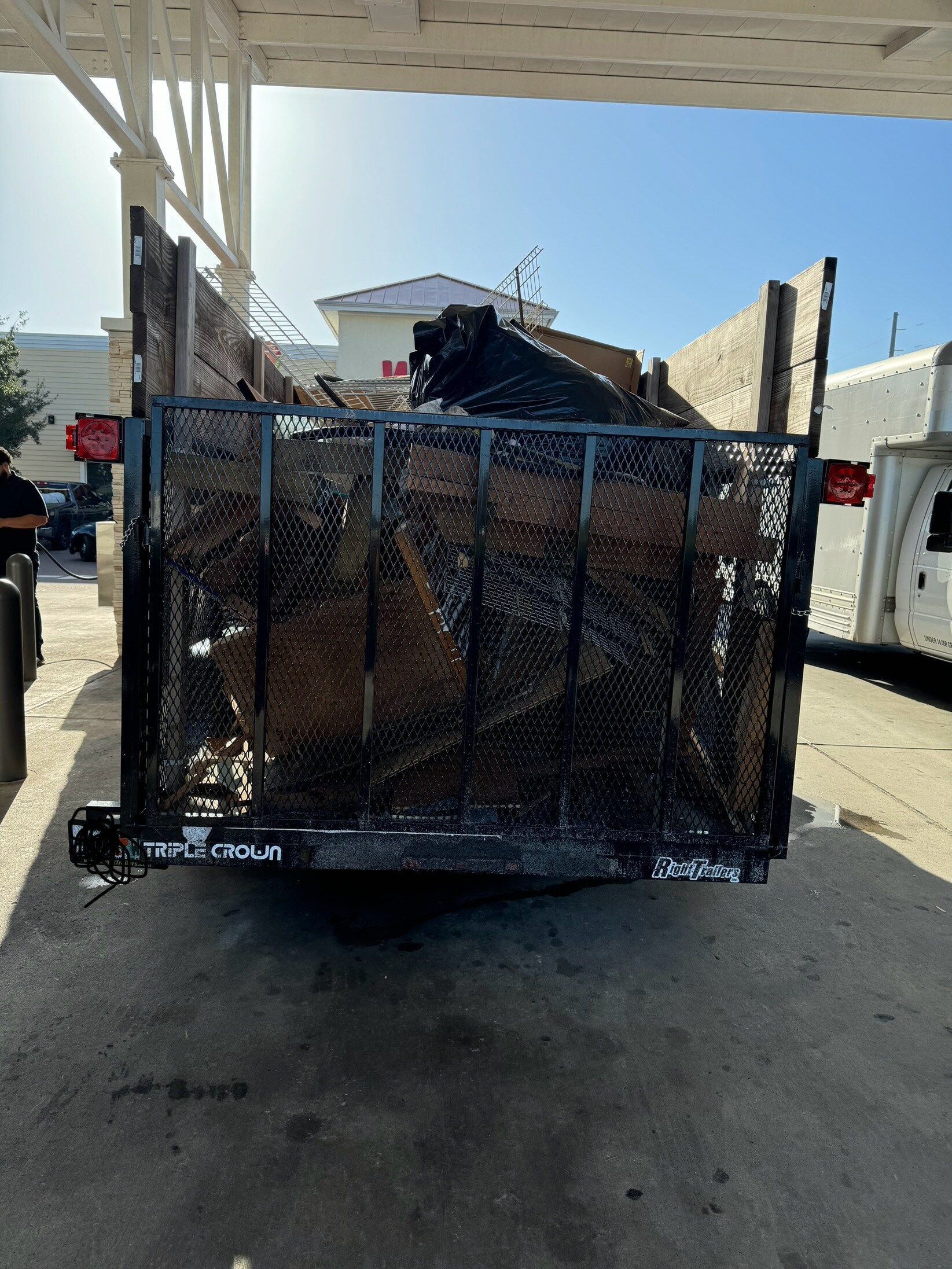 A dumpster filled with a lot of trash is parked in a parking lot.