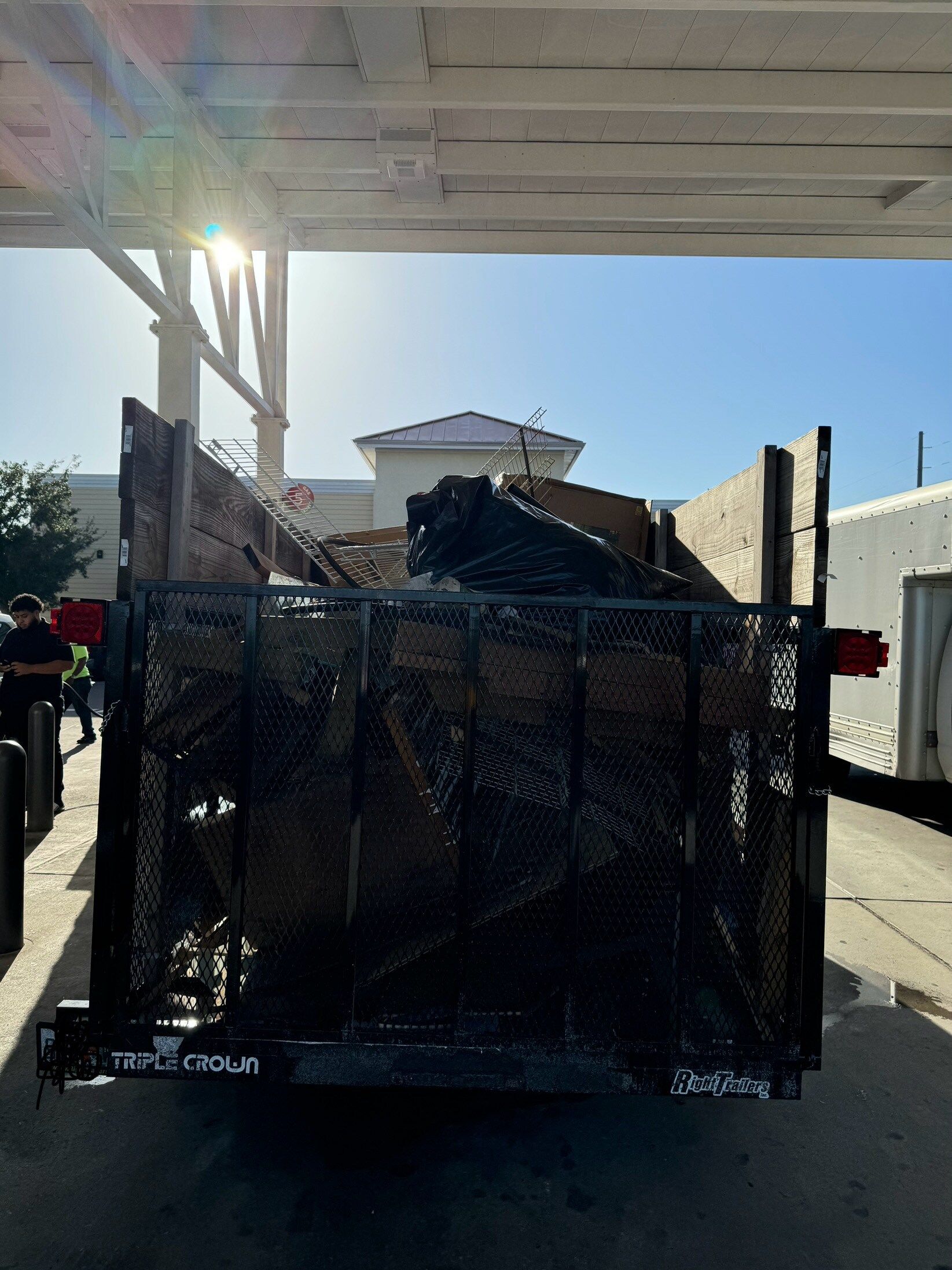 A dump truck is parked under a canopy in a parking lot.