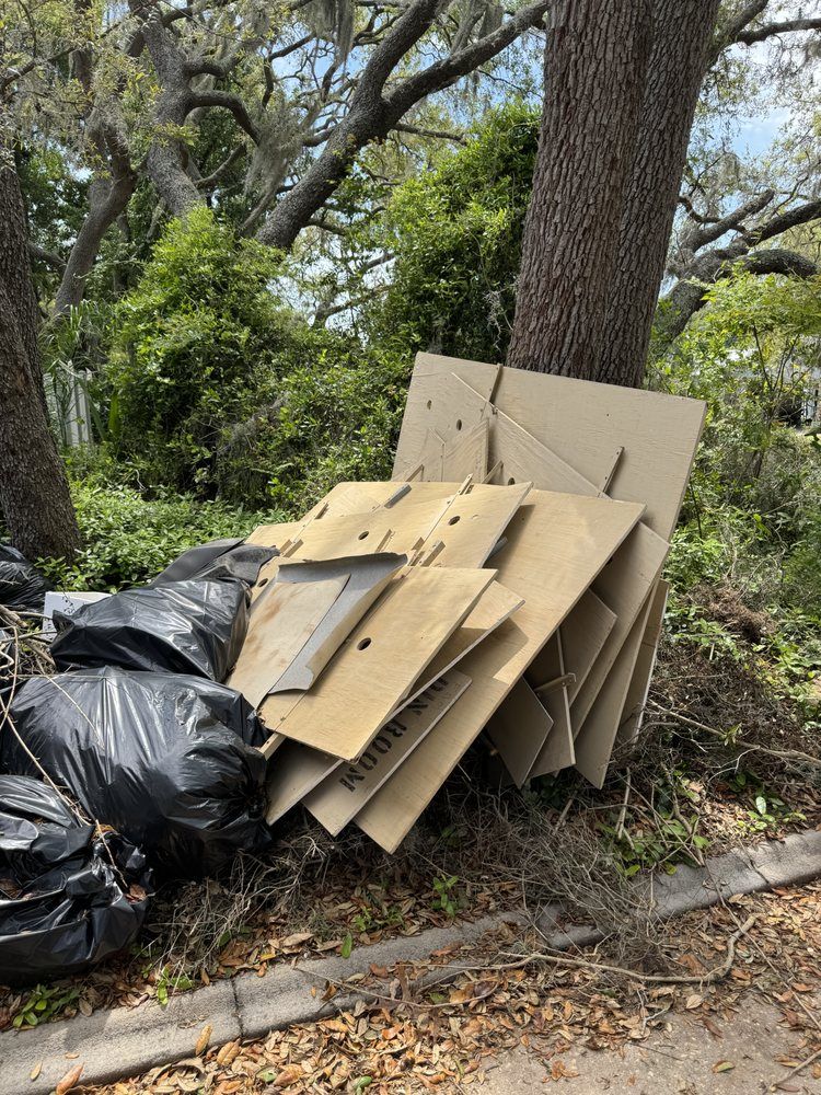 A pile of cardboard boxes is sitting on the ground next to a tree.