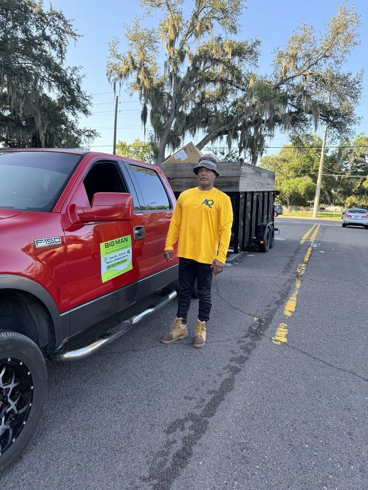 A man in a yellow shirt is standing next to a red truck.