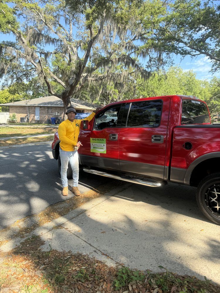 A man is standing next to a red truck on the side of the road.