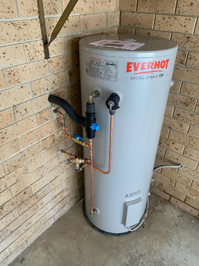 A White Water Heater is Sitting Next to a White Tank in a Room — Wahoo Plumbing in Warana, QLD