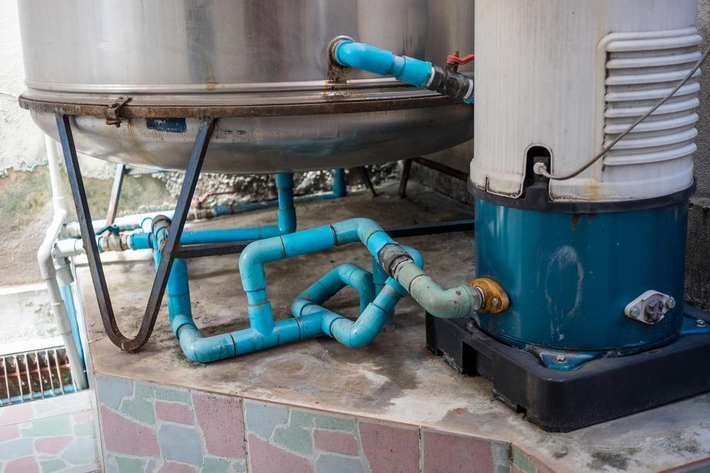 A Water Pump is Sitting Next to a Stainless Steel Tank — Wahoo Plumbing in Kawana Waters, QLD