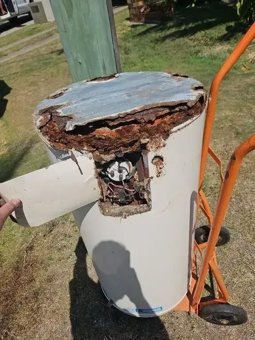 A Person is Holding a Broken Water Heater on a Dolly — Wahoo Plumbing in Wurtulla, QLD