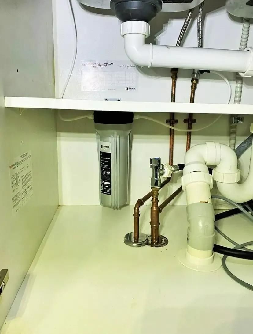 The Inside of a Kitchen Sink With Copper Pipes and a Water Filter — Wahoo Plumbing in Wurtulla, QLD