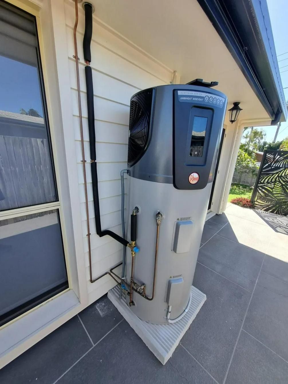 A Large Water Heater is Sitting on the Side of a House — Wahoo Plumbing in Caloundra, QLD