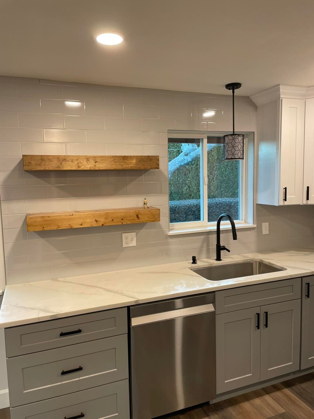 A kitchen with white cabinets , stainless steel appliances , a sink , and a window.