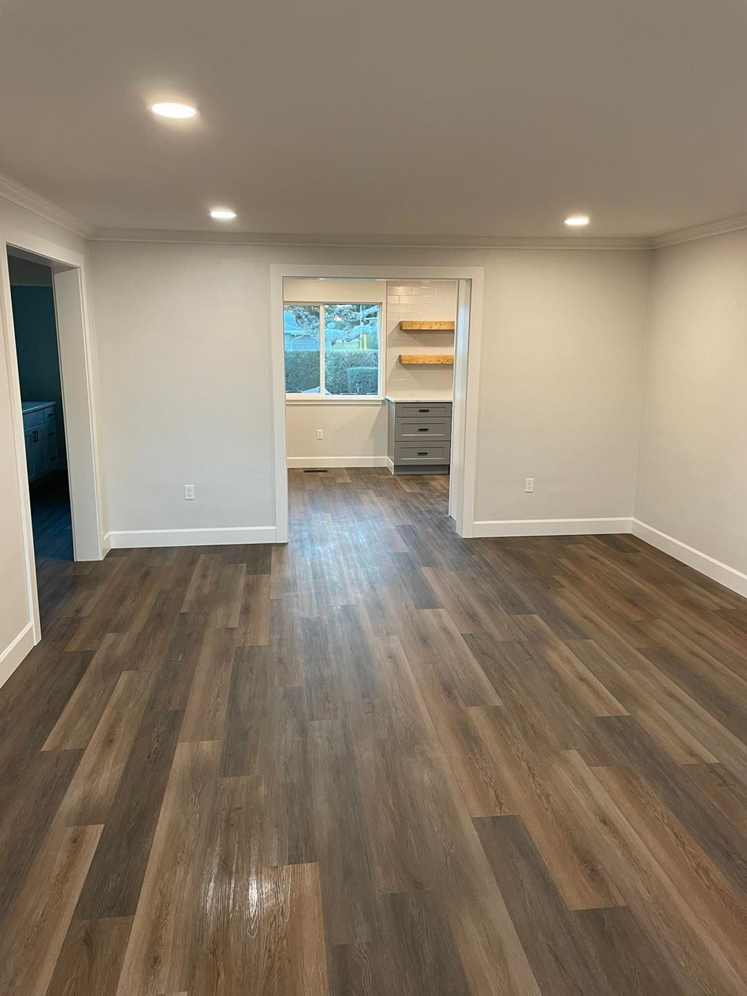 An empty living room with hardwood floors and white walls.