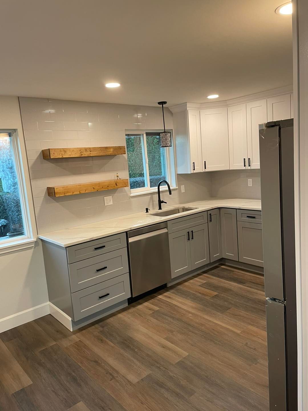 A kitchen with white cabinets , stainless steel appliances , and hardwood floors.